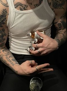 a man with tattoos on his arm holding two bottles