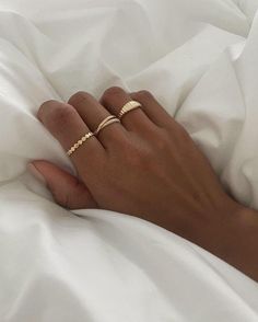 a person's hand with two gold rings on their fingers, laying in bed