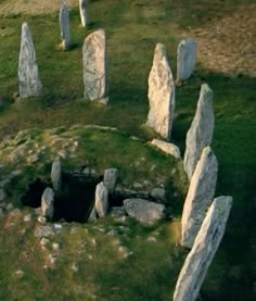 an aerial view of several large stones in a grassy area with grass growing around them