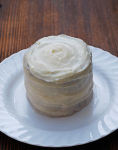 a white plate topped with a cake covered in frosting on top of a wooden table