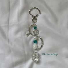 a key chain with beads and charms attached to it on a white sheeted surface