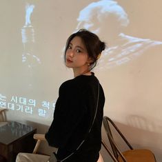 a woman standing in front of a projector screen with an image of a man on it