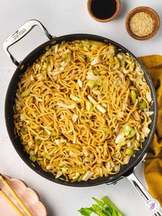 a pan filled with noodles and vegetables on top of a table next to other ingredients