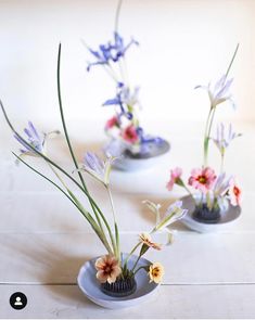 three small vases with flowers in them on a table