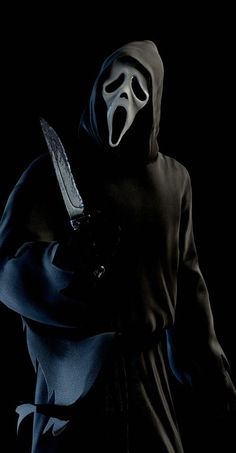 a person wearing a mask and holding a knife in their hand with a black background