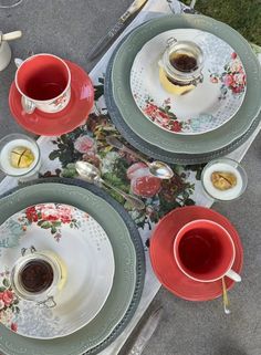 two cups of tea sit on plates with saucers and spoons next to each other