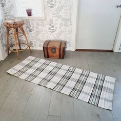 a rug on the floor in front of a door with a basket and stool next to it