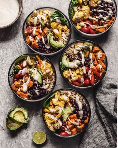 four bowls filled with different types of salads next to avocado and dressing