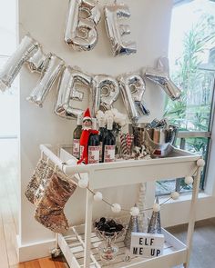 a white table topped with lots of silver foil balloons and christmas decorations on top of it