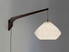 a white light hanging from the side of a wall next to a wooden lamp holder