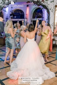 a group of women standing around each other on top of a dance floor with their arms in the air