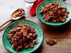 two green plates filled with pecans on top of a wooden table