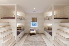 a room with bunk beds and white walls, carpeted flooring and wooden stairs