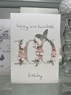 a birthday card with flowers and butterflies on it, next to a bottle of water