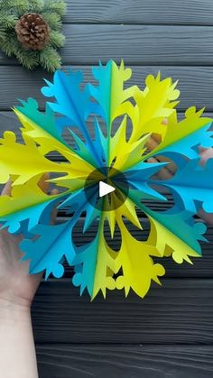 a hand holding a paper snowflake on top of a wooden table