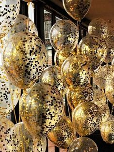 gold and white balloons are hanging from the ceiling in front of a window with black polka dots