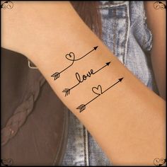 a woman's arm with an arrow and heart tattoo on it