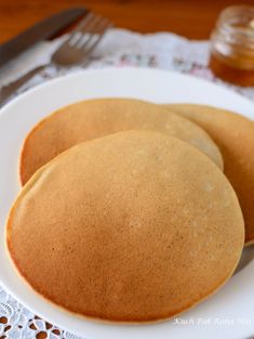 two pancakes on a white plate next to a fork