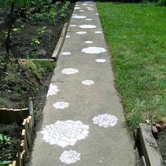 a sidewalk with white flowers painted on it in front of some trees and bushes,