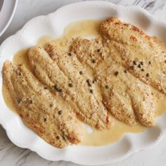 some kind of food that is on a white plate and next to a bowl with sauce