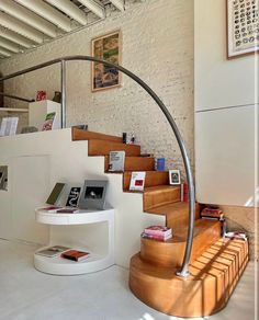 there is a spiral staircase in the living room with books and magazines on the table