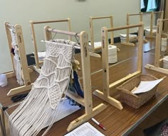 several weaving machines are lined up on a table with paper and yarn in front of them