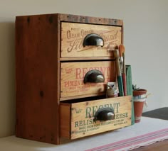 an old wooden box with two drawers and some tools in it on top of a table