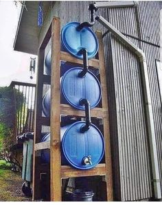 a wooden shelf with three blue water tanks on it's sides and an open door in the background