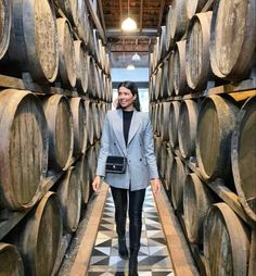 a woman standing in front of many wooden barrels