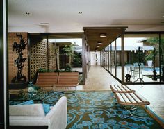 a living room filled with furniture next to a swimming pool on top of a wooden floor