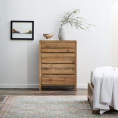 a white vase sitting on top of a wooden dresser next to a bed in a room