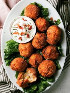 a white plate topped with meatballs covered in sauce and lettuce next to a small bowl of ranch dressing