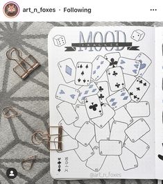 an open notebook with playing cards on it and some clips to hold them in place