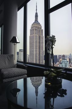 a living room with large windows and a view of the empire building in new york city