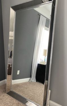 a large silver mirror sitting on top of a carpeted floor next to a wall