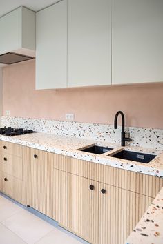 a kitchen with two sinks and cabinets in the middle, one has a black faucet