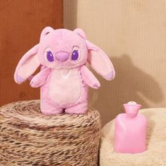 a pink stuffed animal sitting on top of a pile of blankets next to a bottle