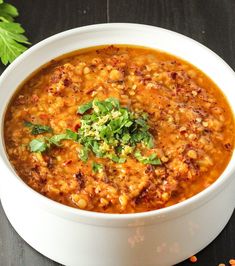 a white bowl filled with soup and garnished with cilantro on top