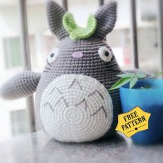 a crocheted stuffed animal sitting next to a potted plant on a table