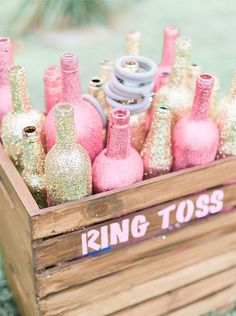 a wooden crate filled with pink and gold bottles