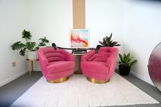 two pink chairs sitting next to each other on top of a white carpeted floor