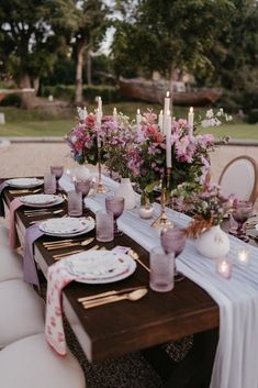 a table set with candles, plates and napkins for an elegant dinner party setting