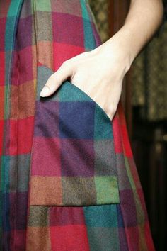 a woman's hand is holding onto a colorful plaid skirt that has been folded over