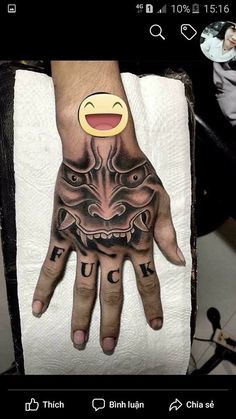 a person's hand with a tattoo on it and an emoticive face