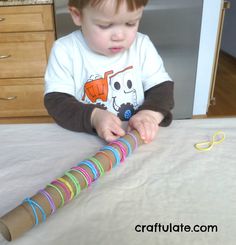 a little boy that is sitting at a table with some paper tubes in front of him