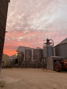 a farm with silos at sunset in the background and a pink sky behind it