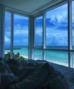 an ocean view is seen through the windows of a bedroom with a bed in front of it