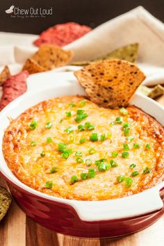 a red casserole dish filled with cheese and green onions