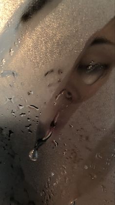 a woman's face is seen through the water droplets on her glass window as she looks into the camera