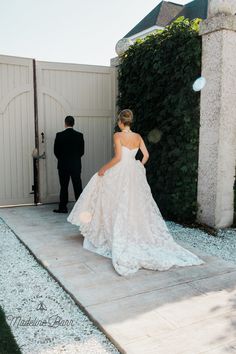 a woman in a wedding dress is walking towards the groom